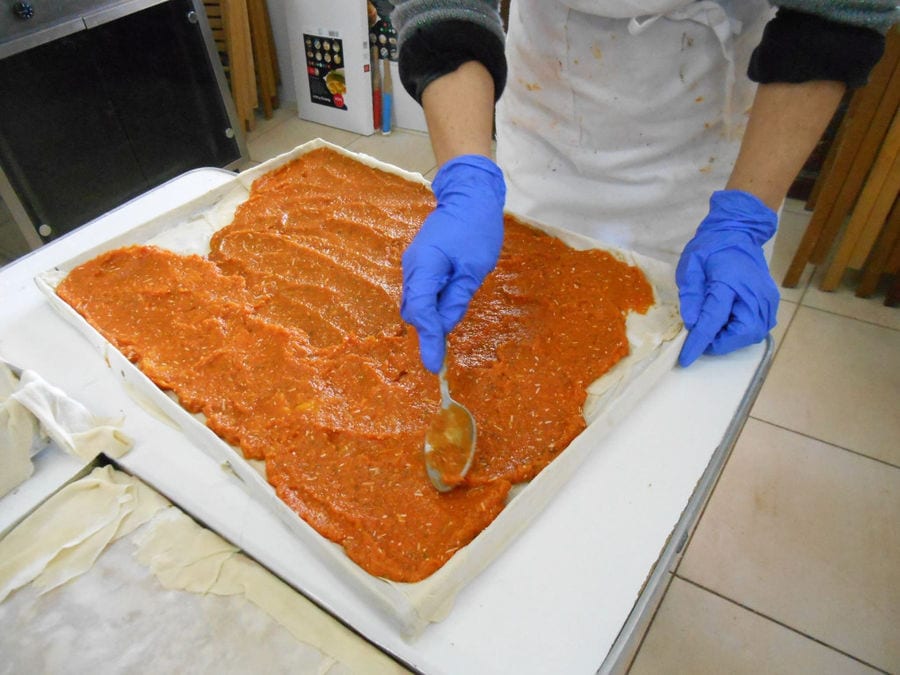woman laying pasta of pumpkins on filo dough with a spoon at 'Agrotouristic Women's Cooperative of Mesotopos Lesvos'